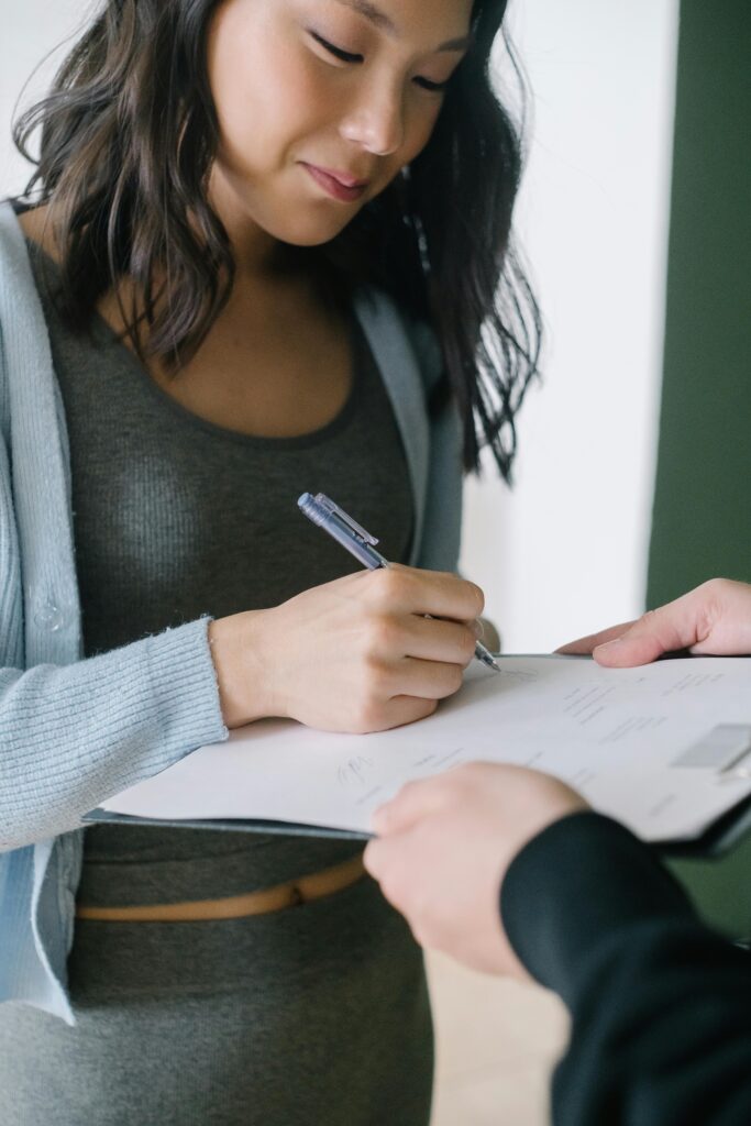 Close-up of a woman signing a document, showcasing business professionalism.